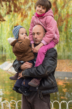 Father carrying son and daughter piggybacks
