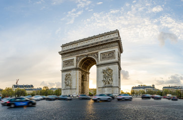 Fototapeta na wymiar The Arch of Triumph in Paris, France on a sunny spring sunset with cars moving all arond the intersection at this beautiful landmark
