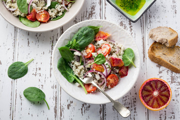 Healthy spring salad with quinoa, fresh spinach and blood oranges on white rustic background