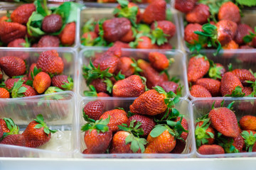 Bunch of fresh strawberry in plastic boxes in cool place in supermarket