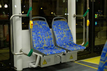 Interior of modern city low floor city tram with seats and hand grips in night