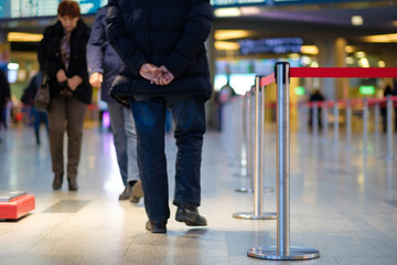 Fototapeta na wymiar Stanchion barriers for waining lines in front of check in desks in airport on blurry background with passengers