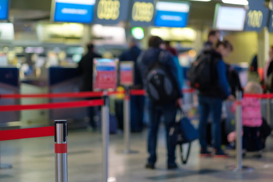 Stanchion Barriers For Waining Lines In Front Of Check In Desks In Airport On Blurry Background With Passengers In Queue