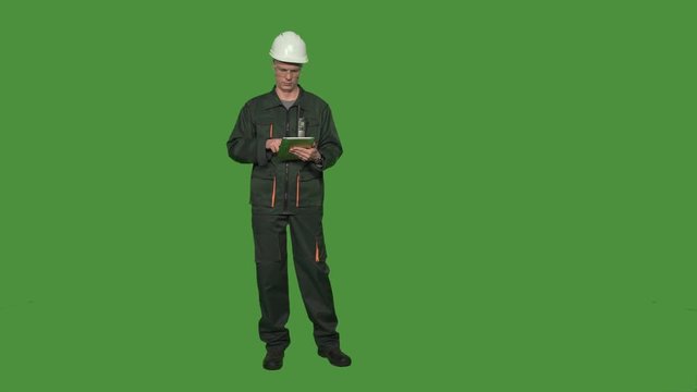 Engineer in protective suit with hard hat and digital tablet islated on green screen