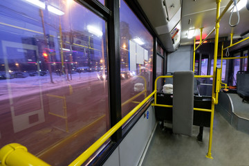Interior of modern city trolley bus in front part making turn on junction in night