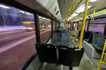 Interior of modern city trolley bus in back part with doors in night