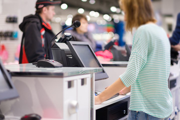 Cash desk with computer screen and cashier serves customers in clothes store