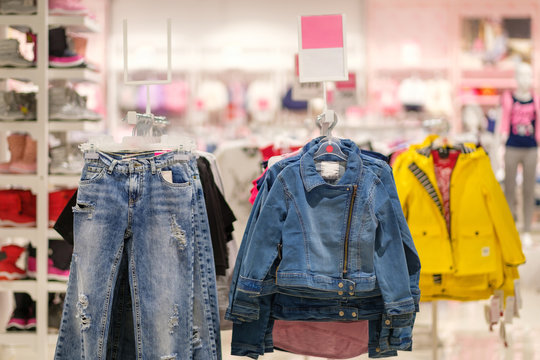 Variety of jeans jackets and jeans for girls on hangers in kids clothes store