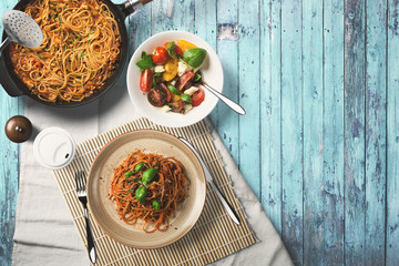 Pasta and salad, wooden desk, top view.