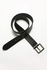 Black leather belt lying on a white background