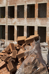 Stack of perforated bricks near the unfinished building