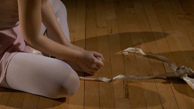 Dancer takes off ballet shoes and rubs her feet