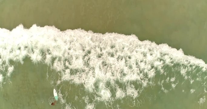 Aerial drone footage of surfer fallen from the wave and ocean waves reaching shore. Drone follows the wave smoothly. Phuket.Thailand 2017.