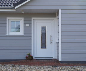 Weiße Haustür mit grauer Holzwand