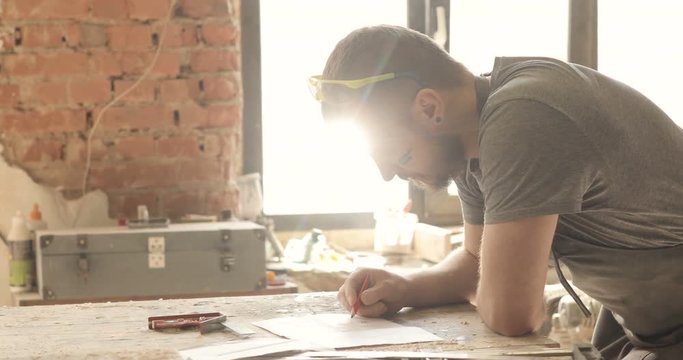Carpenter draws, close-up, in carpentry workshop