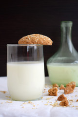 Oatmeal cookies with milk on a black and white background. A bottle of milk in the background. Pieces of cookies and oatmeal.