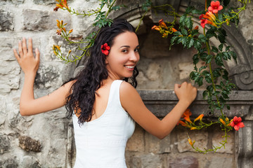 Beautiful happy woman posing in front of a wall and smiling
