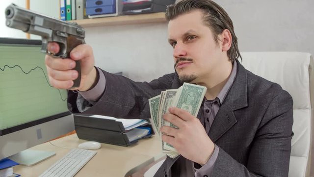 A boss is sitting in his office and he is pointing a gun at someone. He is also having money in the other hand.
