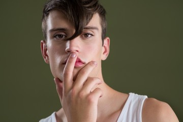 Androgynous person posing with finger on lips