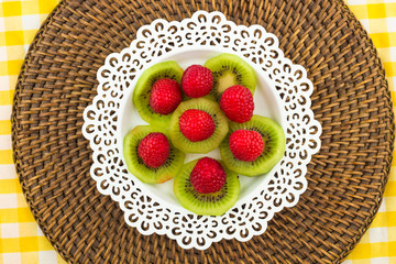 Fresh Red Raspberries on a white artistic plate / Red Fresh Raspberries on a white artistic plate with cookies, rosemary, chocolate and cream in the background.