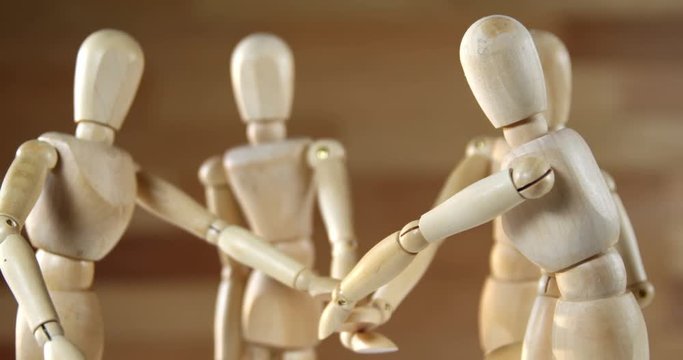Wooden figurines representing businesspeople forming a handstack