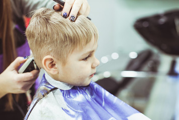 Little boy makes hairstyle at the hairdresser