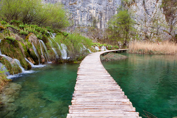 Fototapeta na wymiar Wooden tourist path goes trhough waterfalls in Plitvice Lakes National PArk, Croatia
