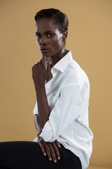 Androgynous person in white shirt posing against beige background
