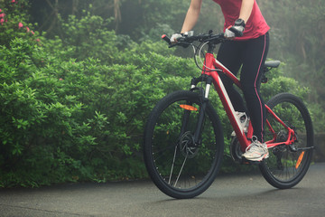 Naklejka premium Young woman riding mountain bike on forest trail