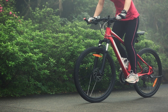 Young woman riding mountain bike on forest trail