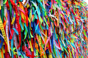 Colorful ribbons in front of a catholic church called Senhor do Bonfim in Salvador, Bahia in Brazil. Famous touristic place where people make wishes while tie the ribbons in the Carnival land. - obrazy, fototapety, plakaty
