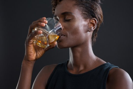 Androgynous person drinking whiskey from glass