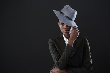 Androgynous man with hand on hat