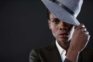 Androgynous man with hand on hat against grey background