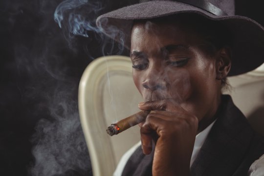 Androgynous person smoking cigar while sitting on a chair - Powered by Adobe