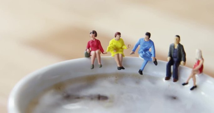 Miniature business people sitting on the edge of the coffee cup