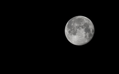 Full Moon in the dark night, black background, isolated. Detailed craters. Right side. Copy space.