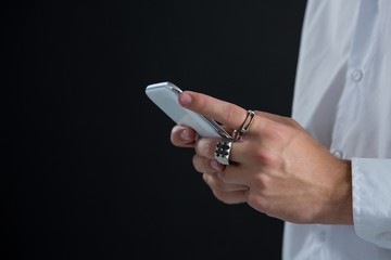 Androgynous man using mobile phone against black background