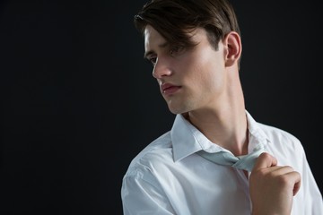 Androgynous man adjusting his tie