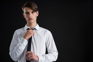 Androgynous man adjusting his tie