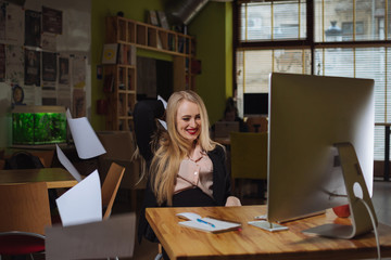 Young excited businesswoman throwing files in the air in office