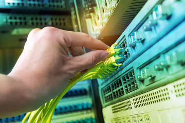 hand of administrator holding network cables connected to servers