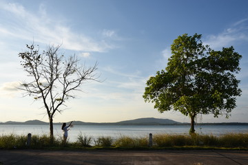 Fototapeta premium Women stand on the Gulf of Thailand at sunset.