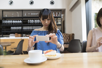 A woman is shooting on a mobile phone before eating a cake