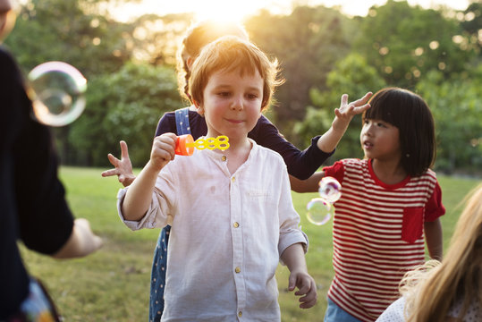 Group of kindergarten kids friends playing blowing bubbles fun