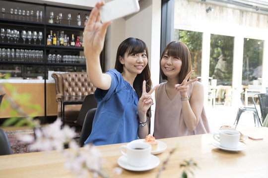 Women are taking self photos at a cafe