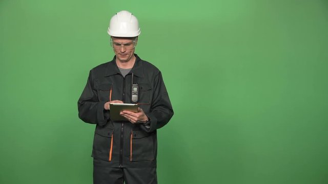 Engineer in protective suit with hard hat and digital tablet islated on green screen