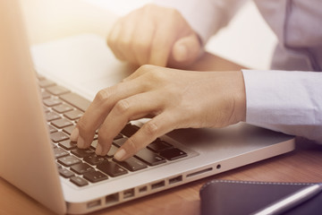 Close up of female hands typing on laptop keyboard at the desk.