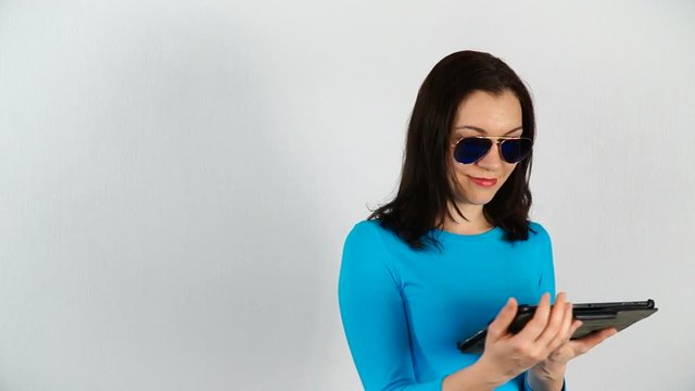 The model works with a digital tablet. Woman of European appearance in sunglasses on a white background.