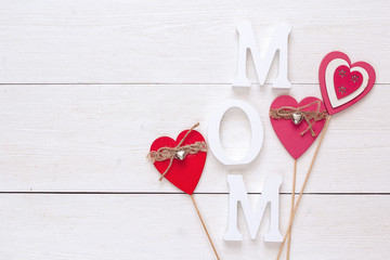 Mothers day message with decorative hearts on a white wooden background.